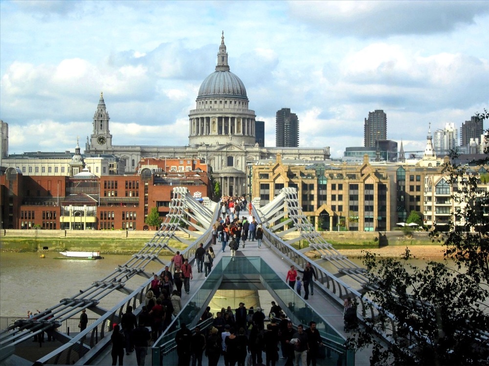 This is a photograph looking north over the Millennium Bridge and the River Thames at the buildings in front of St Paul's Cathedral in London, England.