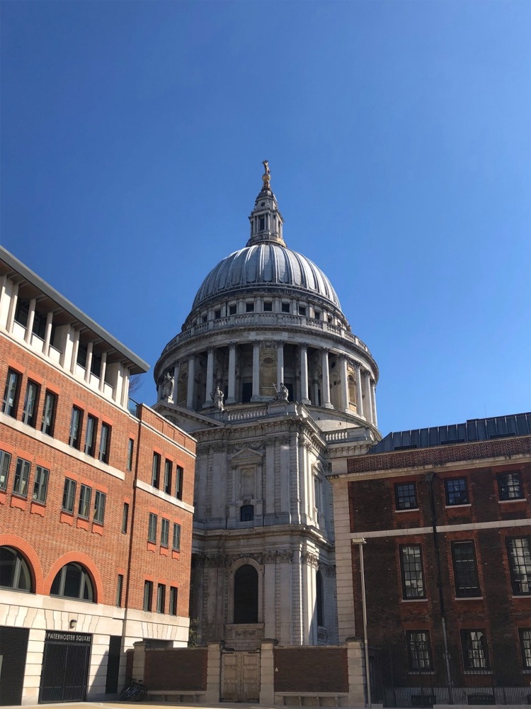 Through a gap between two buildings, this photograph shows the north facade of St Paul's Cathedral in London, England from Paternoster Square.