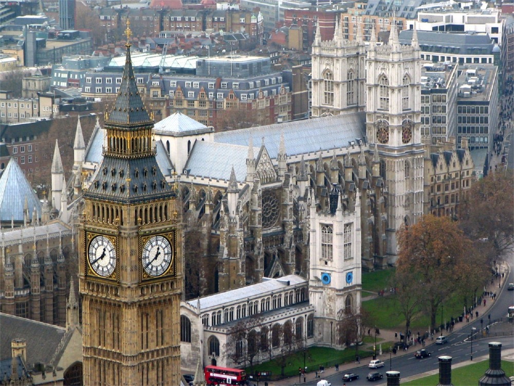 This photograph shows Big Ben in front of the northern facade of Westminster Abbey in London, England.