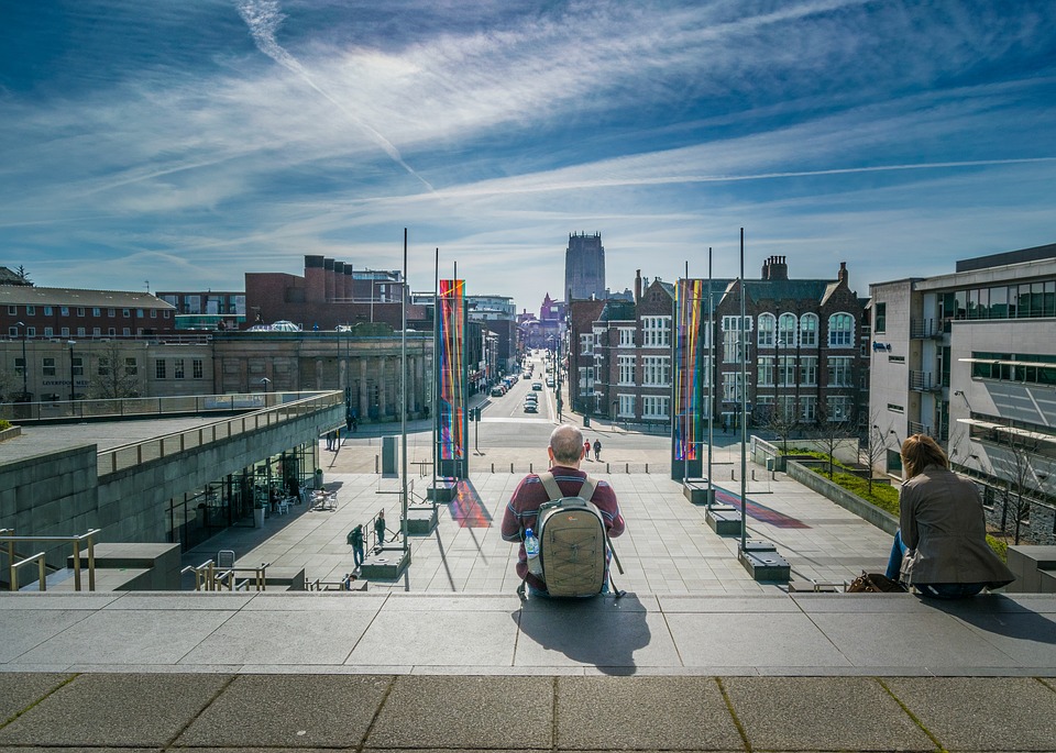 Two people sitting on stairs looking at a view of Liverpool, England, UK, United Kingdom